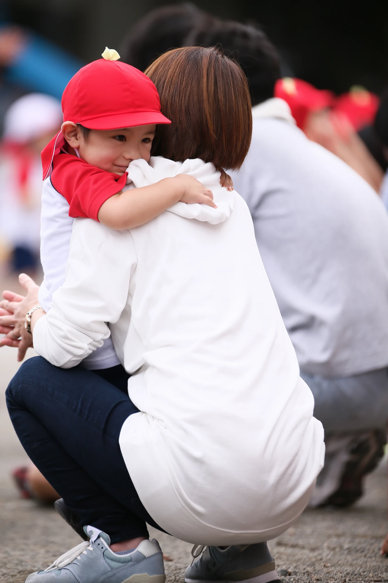 赤い帽子のお子さまが大人に抱きつく姿