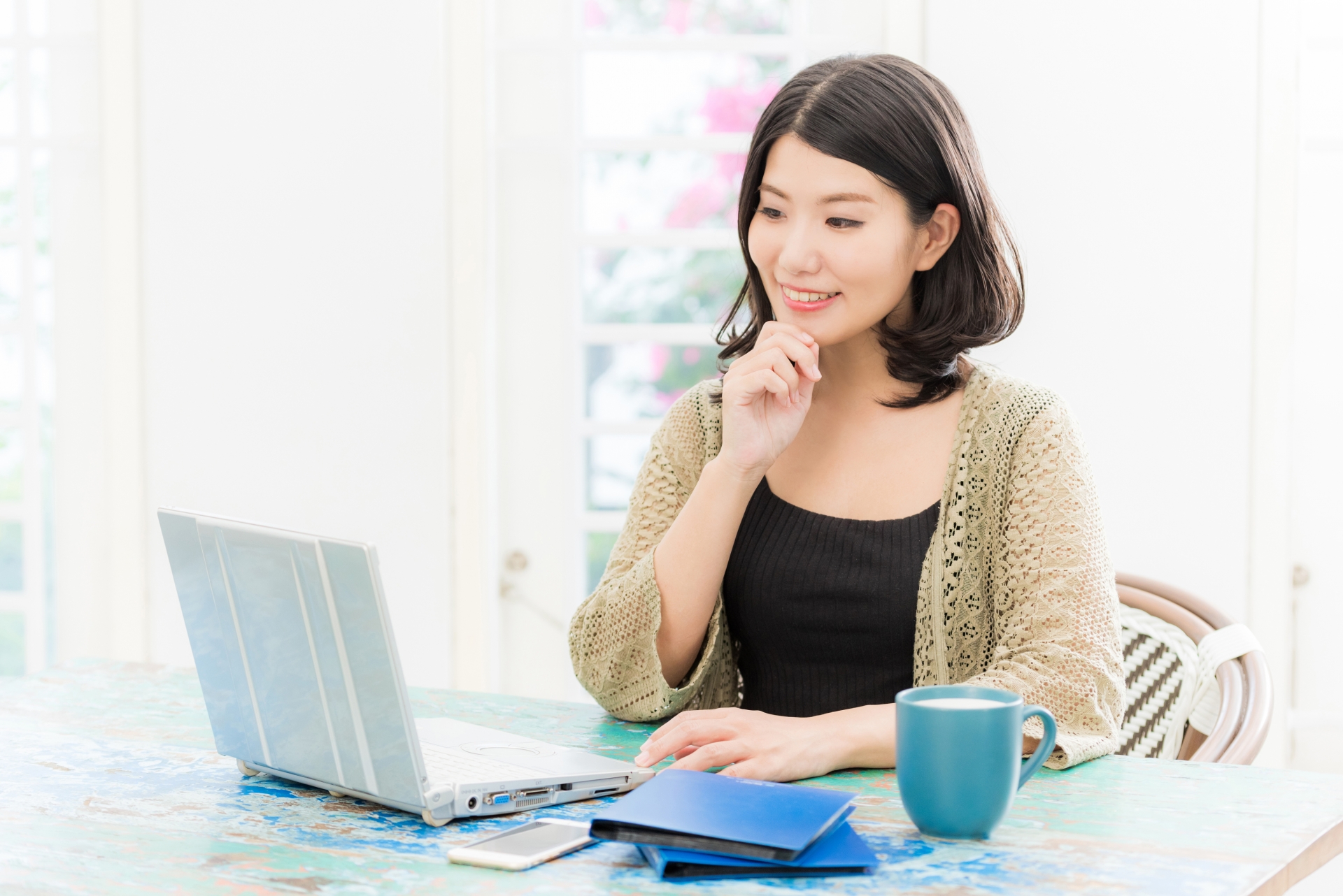明るい室内でノートパソコンに向かう女性