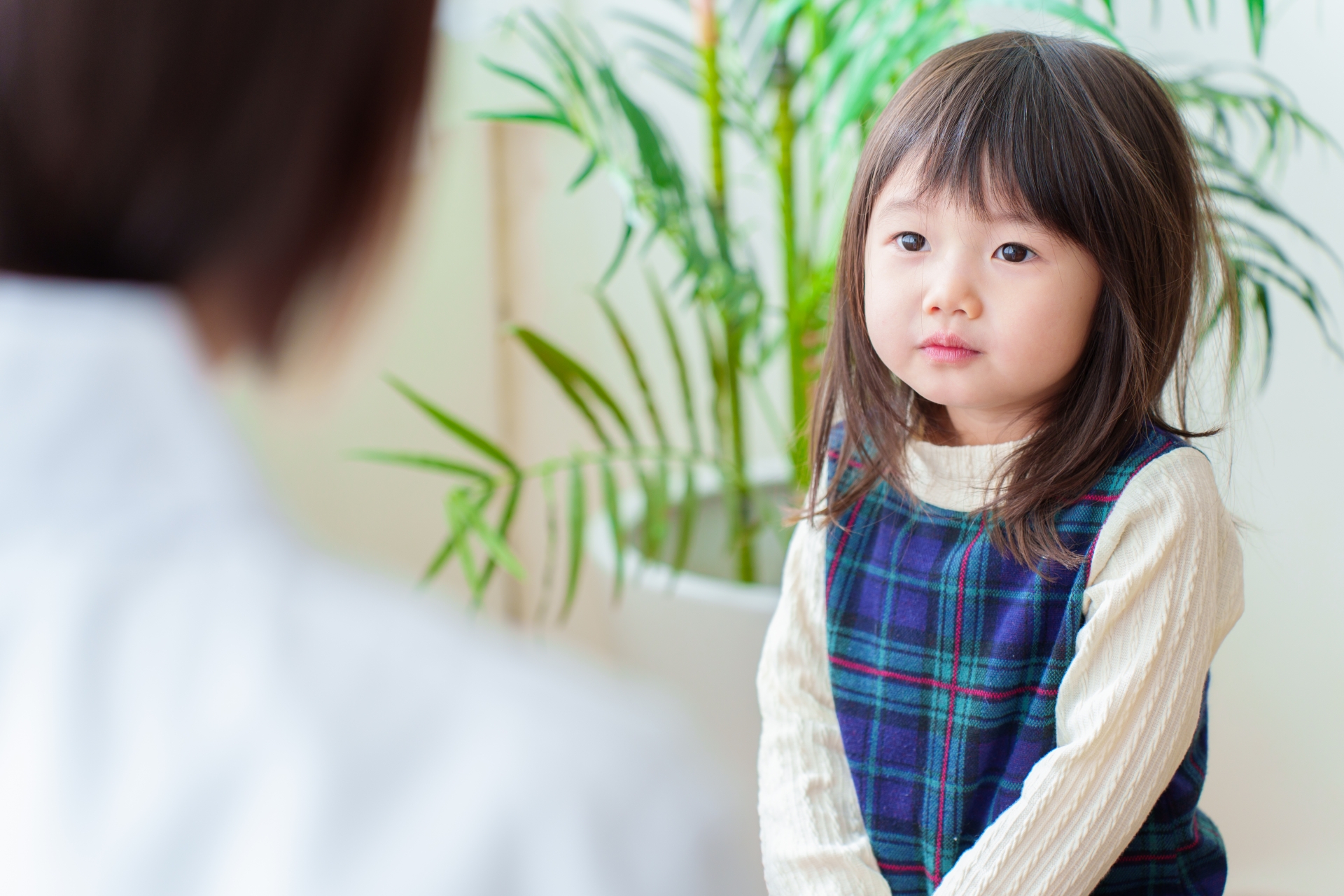 向かい合う大人の話を聞くお子さま